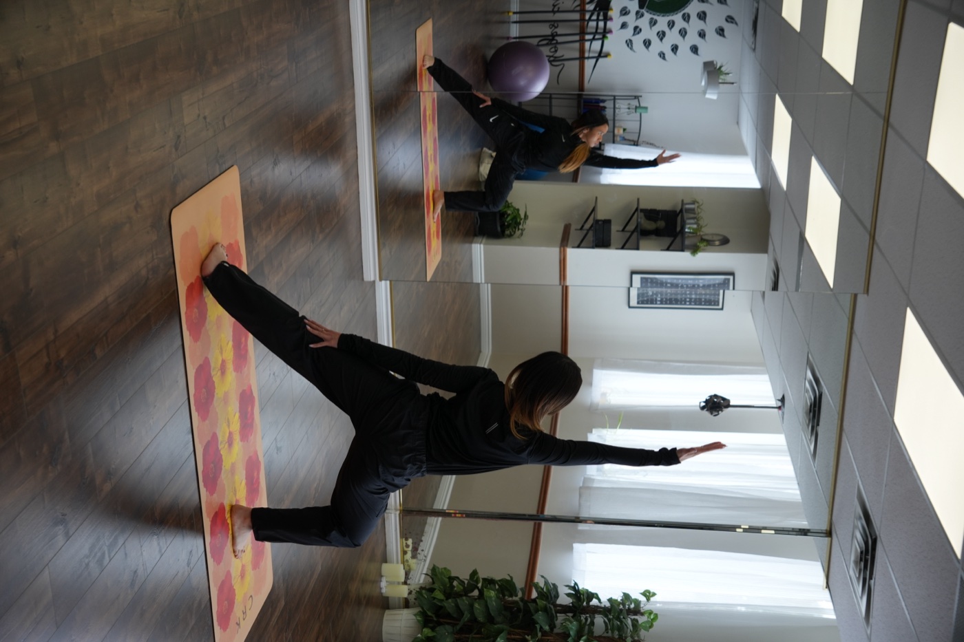 Katrina in a lunging yoga pose in the studio, mirrored behind her